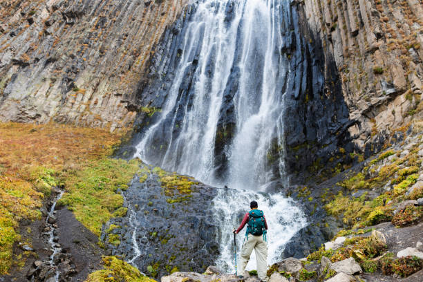 Mid adult woman resting near waterfall while trekking in mountains