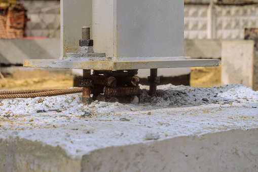 The base of a mounted metal column exposed at the design elevation on a concrete grillage before concreting. Close-up.