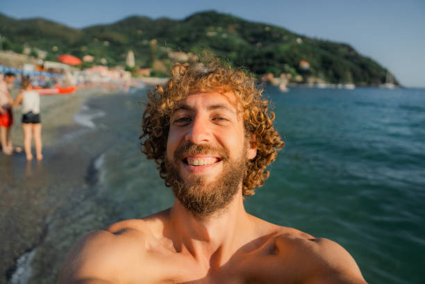 Selfie of cheerful  curly man on vacation on Mediterranean coast in Italy