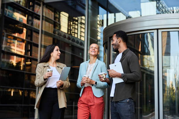 istock Smiling business people with tablets and coffee standing outside office 2150600707