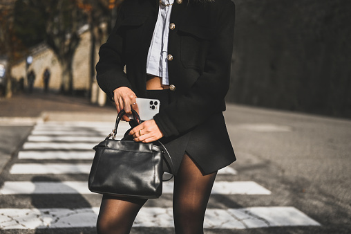 Midsection portrait of a fashionable woman with leather bag and mobile phone.