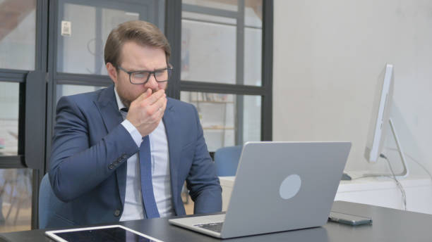 istock Sick Young Businessman Working in Office and Coughing 2150602464