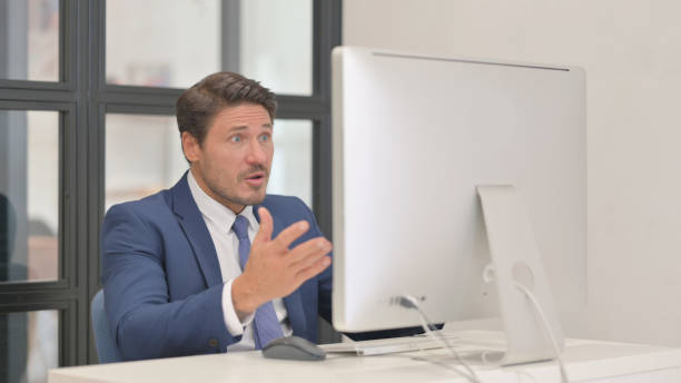 istock Middle Aged Businessman Shocked by Loss on Desktop 2150605570