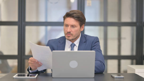 istock Middle Aged Businessman Working on Documents and Laptop 2150605950