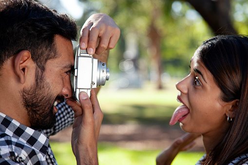 Young man taking photo of a woman with old camera