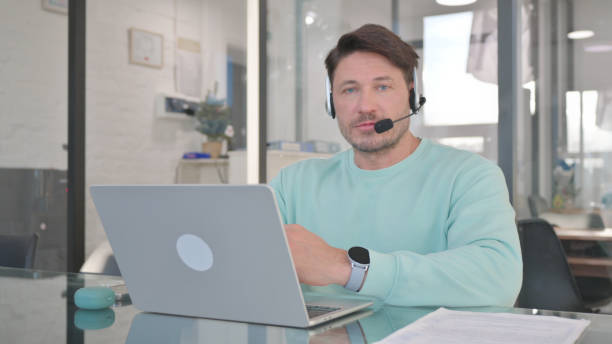istock Man in Call Center with Headset Looking at Camera 2150606618