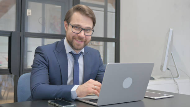 istock Young Businessman Smiling at Camera while Working on Laptop 2150607729