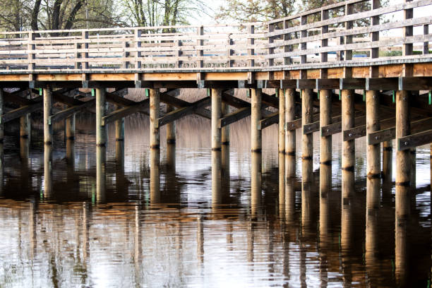 istock Wooden bridge over the river with reflection in the water surface. 2150608346