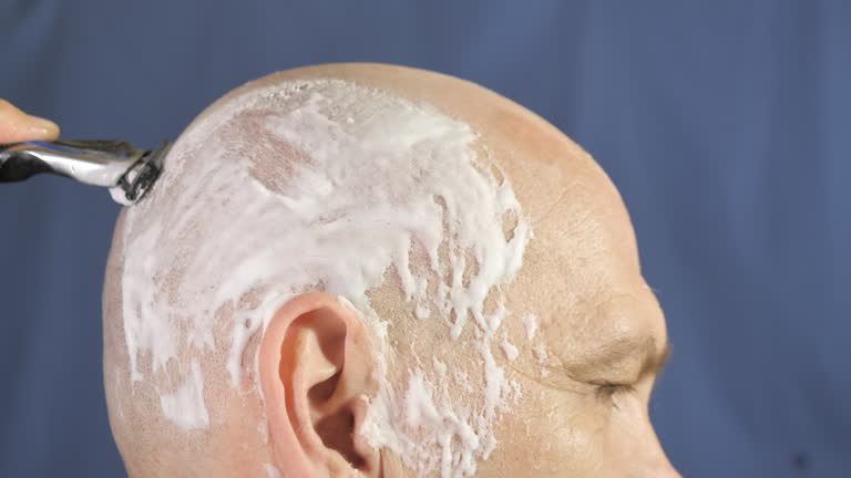 The other side of the head with the shaving cream and the blade moving down.