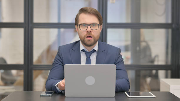 istock Shocked Young Businessman Wondering in Awe while Using Laptop 2150609827