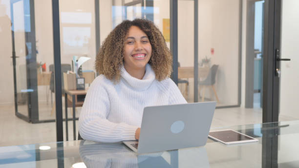 istock African American Woman Smiling at Camera while Working on Laptop 2150610208