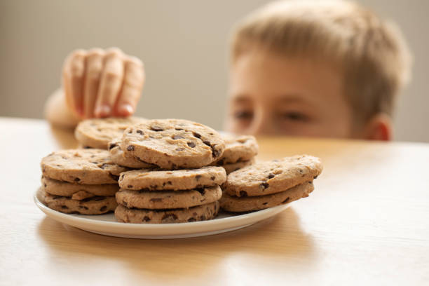 istock A boy is peeping at an appetizing stack of freshly baked chocolate cookies on the table. 2150610901