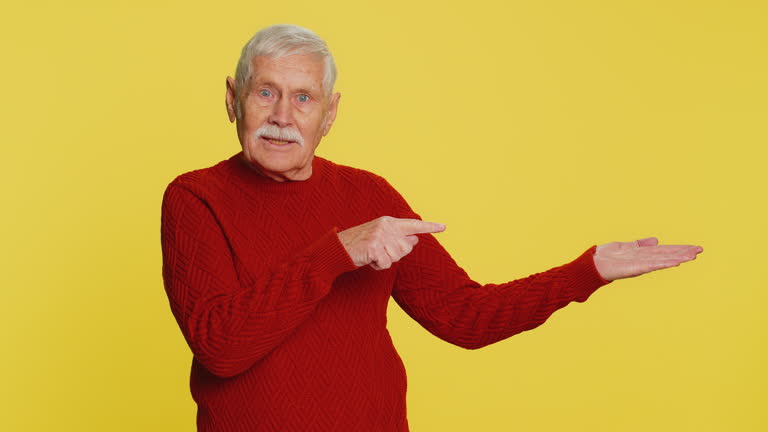 Senior old man showing thumbs up and pointing on blank space place for advertisement promotion logo