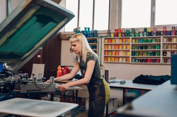 istock Printing shop worker putting screen printing plate on machine. 2150612219