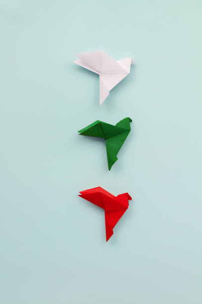 istock three paper origami pigeons white, green and red on light background 2150619170
