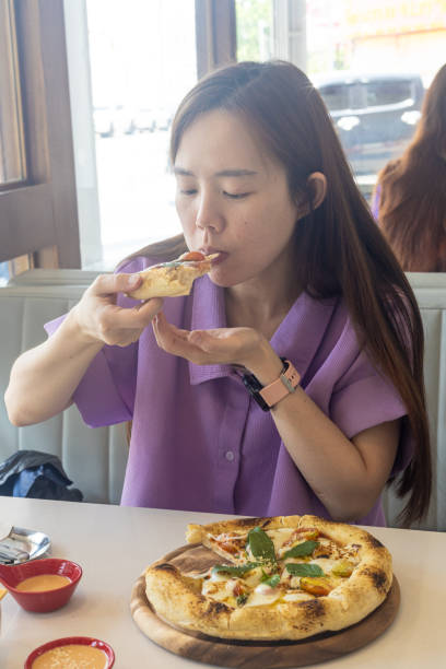 istock A woman is eating a pizza with her hands 2150620390