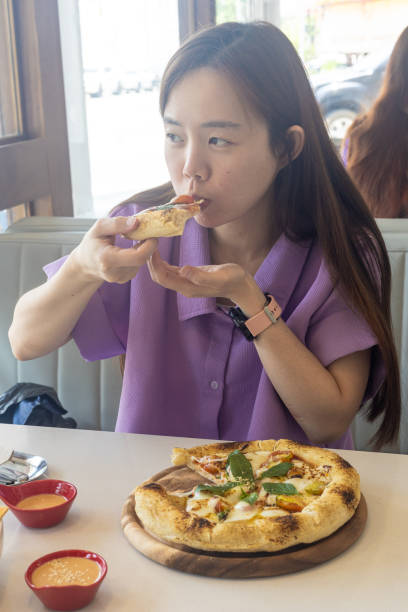 istock A woman is eating a pizza with her hands 2150620402