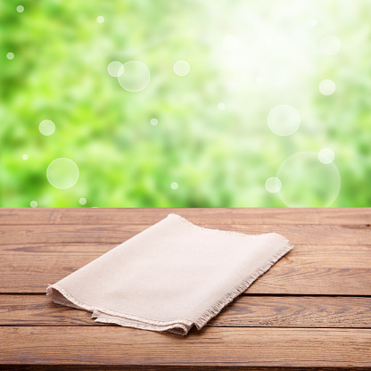 Make your product stand out with this eye-catching napkin mockup, showcasing your design against a natural wood grain. Rustic nature background on a sunny day