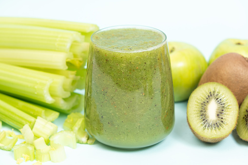 Green smoothie of celery, kiwi, green apple and spinach in a glass.
