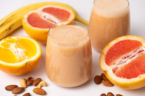 Fruit smoothie in a glass, grapefruit and orange on white background