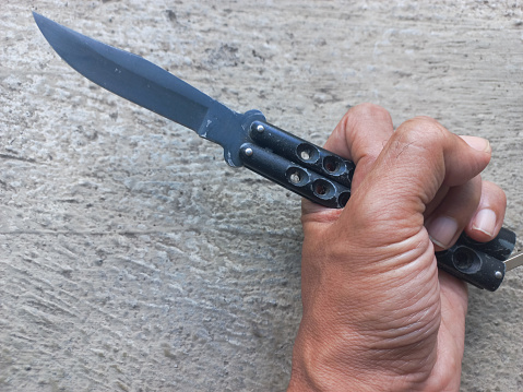 Sharp metal pocket knife in hand. Cold weapon, self-defense tool.
