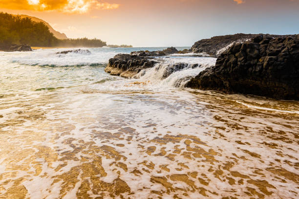 Ocean waves crashing on the sandy beach with the turquoise water rippling and splashing at Lumahai Beach.