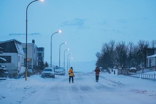 Asian Chinese mature couple tourist walking ini snowing Grundarfjörður, Iceland Small Town in Winter