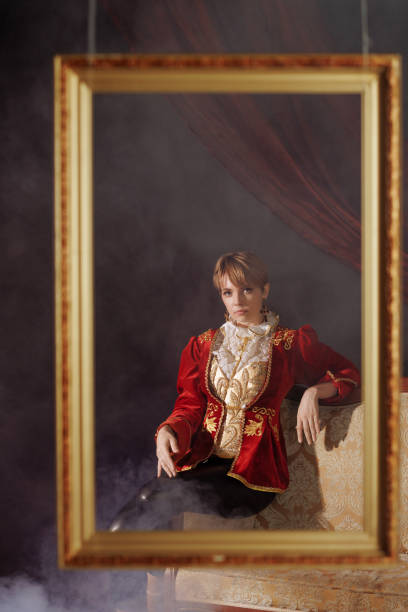 A woman in a red jacket is sitting in front of a gold frame. The concept of historical costumes from the Middle Ages or masquerade.