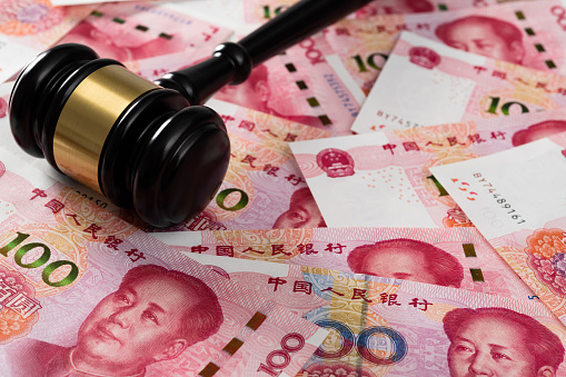 Gavel on stack of Chinese currency.