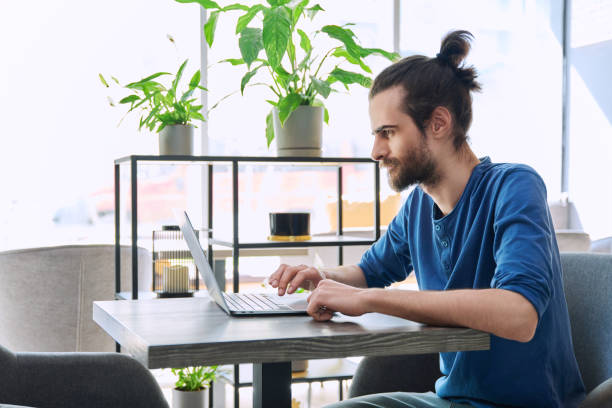 istock Young serious man working, studying, typing on laptop sitting in coworking cafe 2150635724