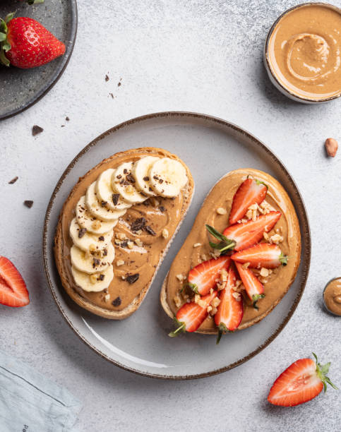 istock Peanut butter sandwiches on ceramic plate. Sliced bread with nut spread, sliced banana and fresh strawberry, chopped chocolate and walnuts. 2150636407
