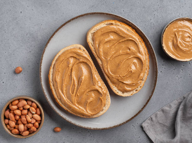 istock Peanut butter sandwiches on grey ceramic plate. Sliced toasted bread with nuts spread, beautifully swirled creamy paste. 2150636410