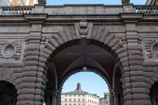 View of The Great Church Storkyrkan Clock Tower from arched gate of Sweden Parliament House, Riksdagshuset Stockholm landmark. Upper part