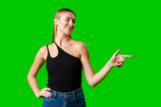 istock Young Woman Pointing at Something against green background 2150640930