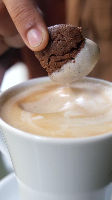 pouring sweet cookies in a coffee mug on wooden table