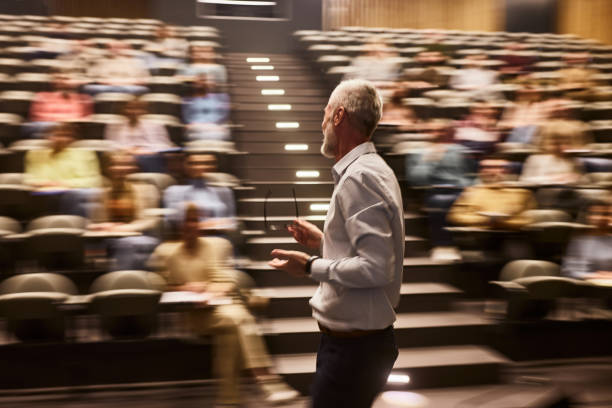 istock Mature professor talking on a class at lecture hall in blurred motion. 2150642449