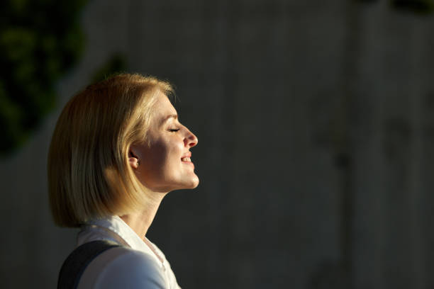 Profile view of happy businesswoman enjoying with her eyes closed while being lightened by sunlight. Copy space.