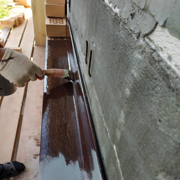 istock A man paints a metal corner with brown paint, working on a construction site. 2150645126