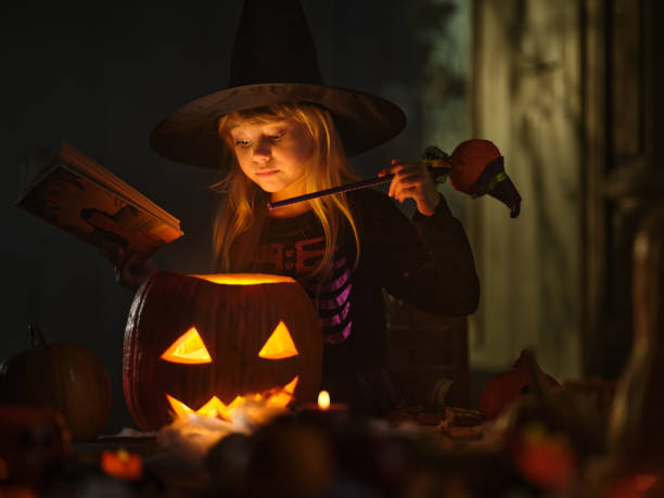 istock Cute little girl casting spells on Jack O' Lantern on Halloween. 2150646171