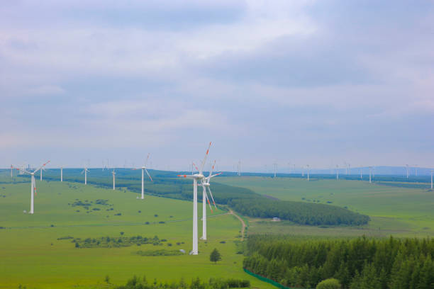Windmills aerial view. Renewable energy. Large wind turbines with blades in field bright Green grassland.