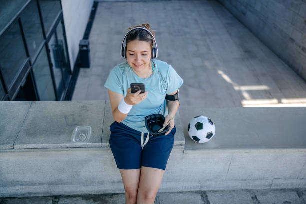 istock Young woman in sportswear using mobile phone while stretching and relaxing outdoors in the city 2150647762