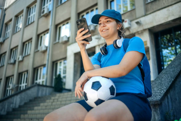 istock Young woman in sportswear using mobile phone while stretching and relaxing outdoors in the city 2150647873