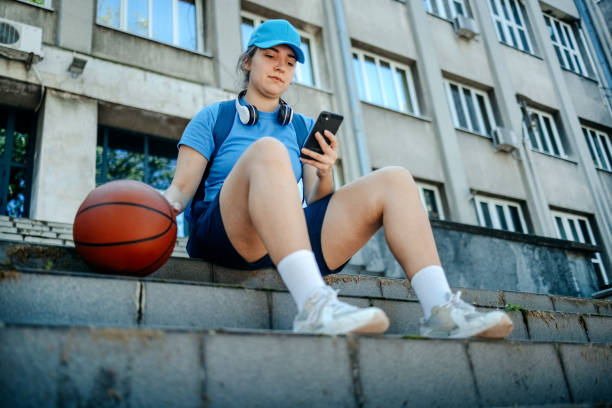 istock Young woman in sportswear using mobile phone while stretching and relaxing outdoors in the city 2150647906