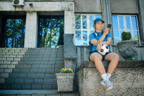 istock Young woman in sportswear using mobile phone while stretching and relaxing outdoors in the city 2150647907