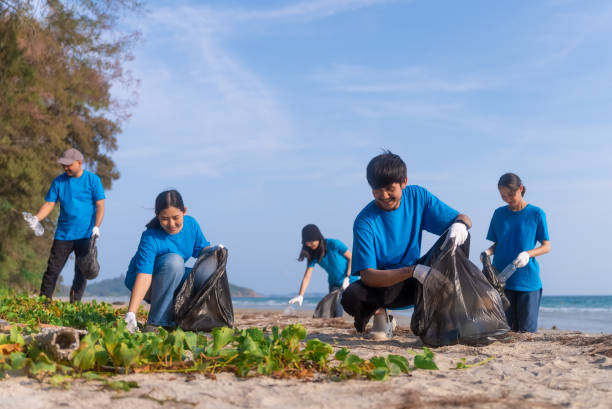 istock Plastic pollution and environmental problem concept. Happy asian diverse group of volunteers with garbage bags wearing blue t-shirt and cleaning plastic on the beach. Volunteers collecting trash. 2150649302
