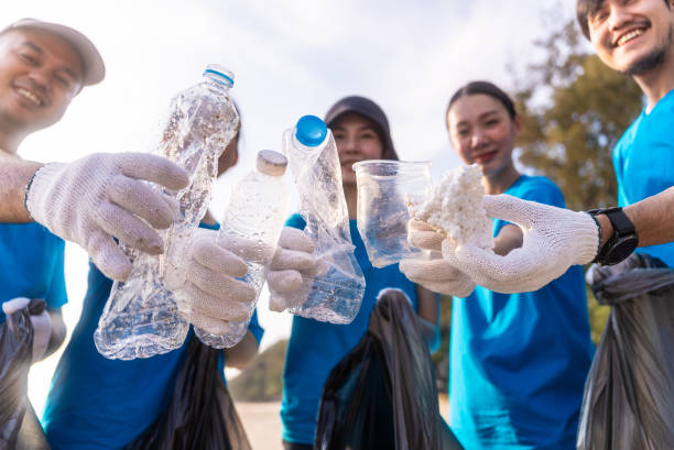 istock Plastic pollution and environmental problem concept. Happy asian diverse group of volunteers with garbage bags wearing blue t-shirt and cleaning plastic on the beach. Volunteers collecting trash. 2150649325