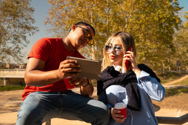 istock Young smiling couple doing watching something on digital tablet sitting outdoors 2150649704