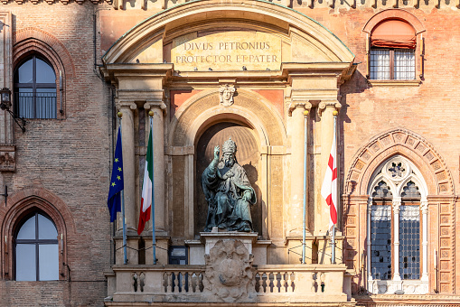 The statue of Pope Gregory XIII sits prominently on the facade of Palazzo d'Accursio in Bologna, flanked by the Italian and European Union flags