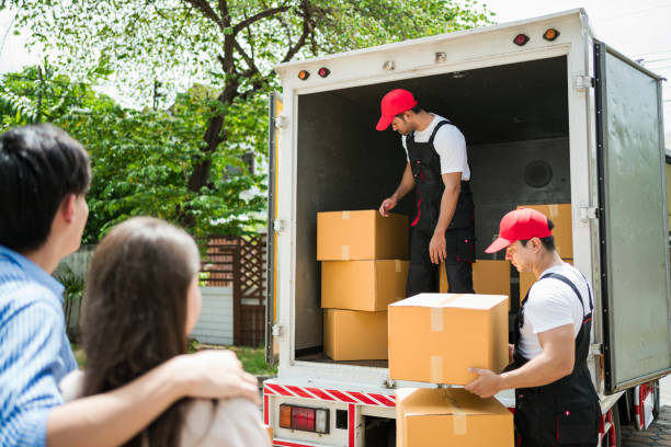 istock Asian and Caucasian workers in uniform unloading cardboard boxes from the truck. Delivery men unloading boxes and check the checklist with their coworkers. Professional delivery and moving service. 2150652900