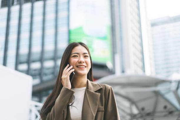 istock Asian business single woman using smart phone talking metropolis city background 2150653384
